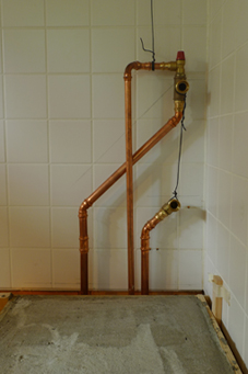 Oben ist der Vorlauf, unten die Rücklaufleitung zu sehen. <br />Zum Vorlauf gehört ein Sicherheitsventil, daß bei zu hohem Kesseldruck öffnet <br />und das Kesselwasser in ein Gefäß im Keller ableitet.<br />Im Vordergrund ist das noch nicht ausgeschalte Betonfundament zu sehen.